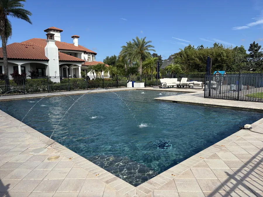 Travertine pool deck and fountain jets at a lakefront home in Oldsmar