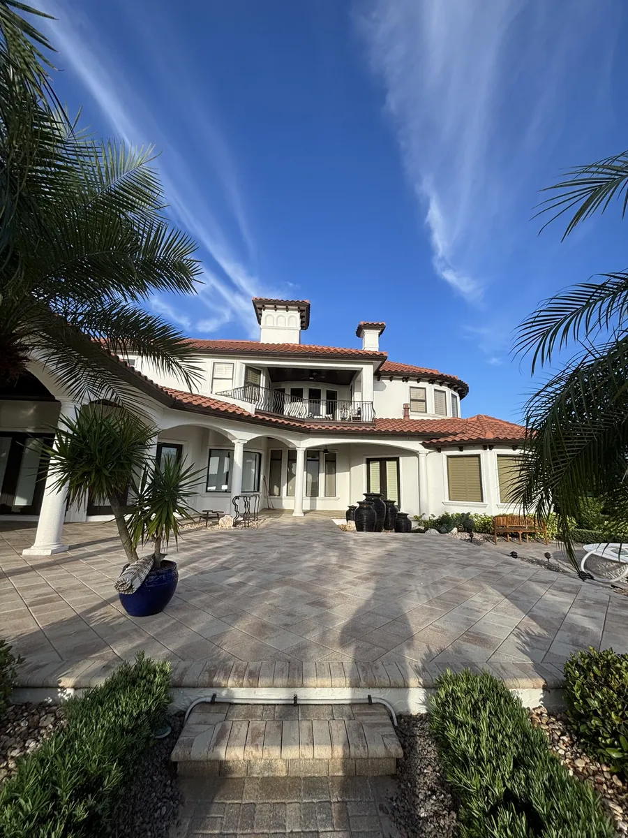 Side of the house with a sealed stone walkway and palms